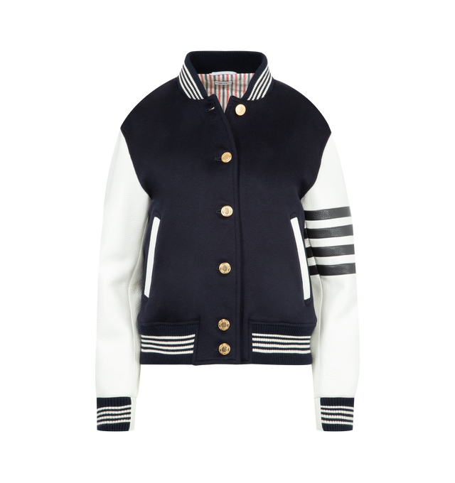Image 1 of 3 - NAVY - THOM BROWNE Browne 65 Varsity Jacket featuring cashmere with leather sleeves, bold BROWNE. lettering and the number 65 on back appliqud in layered silk and cashmere with satin-stitched edges, 4-bar at the sleeve, front button closure, ribbed bomber collar, cuffs, and hem with 4-bar tipping, welt hand pockets with leather trim, three interior pockets, quilted interior, layered appliqu, relaxed fit and signature striped grosgrain loop tab. 100% wool. Lining: 100% silk. Made in Italy.