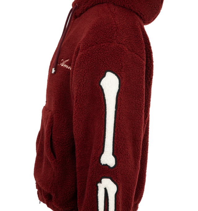 Image 3 of 3 - RED - AMIRI Bones Cotton Fleece Zip-Up Hoodie featuring plush cotton fleece, signature contrast bones patchwork along each sleeve, attached drawstring hood, drop shoulders, long sleeves, split kangaroo pocket and two-way front zip closure. 100% cotton. Made in Italy.