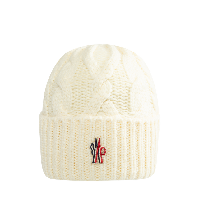 Image 1 of 2 - CREAM - Moncler Grenoble Women's Wool Blend Cable Knit Hat is crafted from a wool blend and features a classic cable-knit construction inspired by alpine textures. Designed as a timeless cold-weather accessory, this beanie is finished with a folded rib-knit cuff and a Moncler Grenoble logo patch at the front. Main Material: Wool Blend.