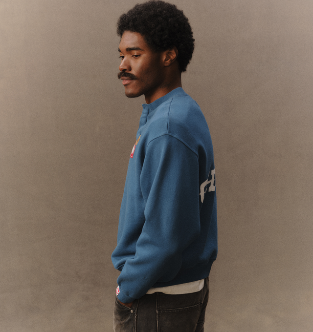 Image 6 of 7 - BLUE - Cherry LA Men's Patch Work Henley Crew is crafted from custom cotton fleece and features a boxy-fit silhouette with patchwork detailing at the chest and a concealed-button Henley placket. Designed for everyday comfort, this elevated sweatshirt is finished with hidden front buttons and a signature branded label at the cuff. Main Material: Custom Cotton Fleece. Made in Los Angeles, California.