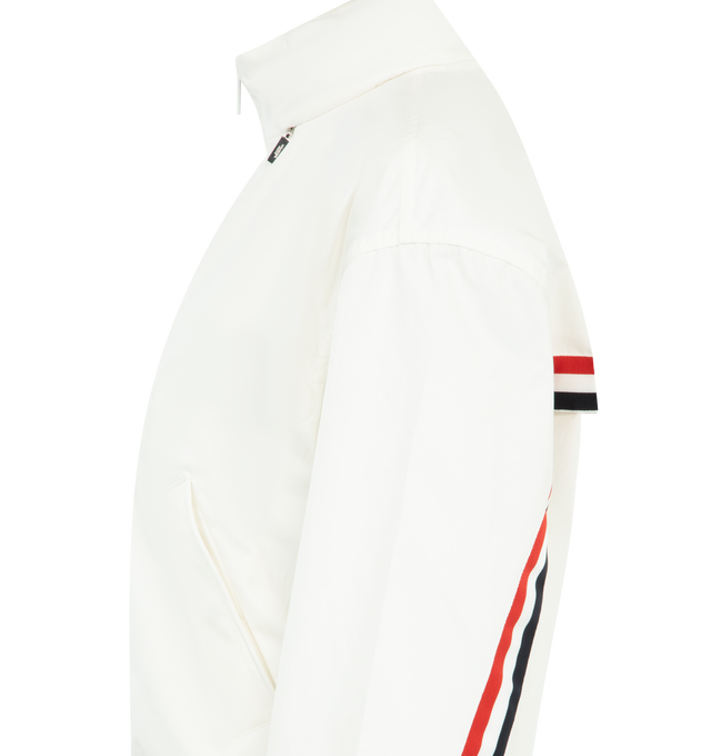 Image 3 of 4 - WHITE - THOM BROWNE Nylon Tech Track Jacket featuring front hidden two-way zip closure, stand collar lined with RWB grosgrain, ripstop drawstring hood that folds into collar with hidden zip, welt hand pockets with hidden snap, back storm flap over mesh panel, RWB grosgrain trim along storm flap and back sleeves, elasticated cuffs and hem with channel stitching and signature striped grosgrain loop tab. 51% polyamide, 49% cotton. Made in Italy.