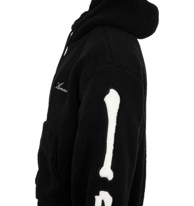 Image 3 of 3 - BLACK - AMIRI Bones Cotton Fleece Zip-Up Hoodie featuring plush cotton fleece, signature contrast bones patchwork along each sleeve, attached drawstring hood, drop shoulders, long sleeves, split kangaroo pocket and two-way front zip closure. 100% cotton. Made in Italy.