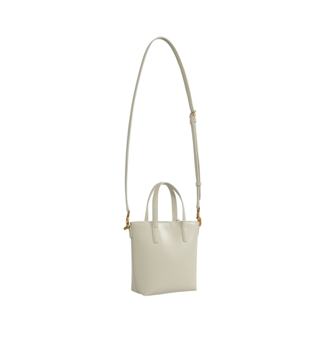 Image 2 of 3 - WHITE - Saint Laurent Mini tote bag embossed with "Saint Laurent Paris" and decorated with a removeable leather-encased Cassandre charm. Features magnetic snap closure, flat leather top handles and an adjustable and detachable strap for multiple carry options.  Lambskin leather with bronze-tone hardware. Measures 7.1" X 6.7" X 3.1" with handle drop 3.3" and strap drop 19.7". Made in Italy.  