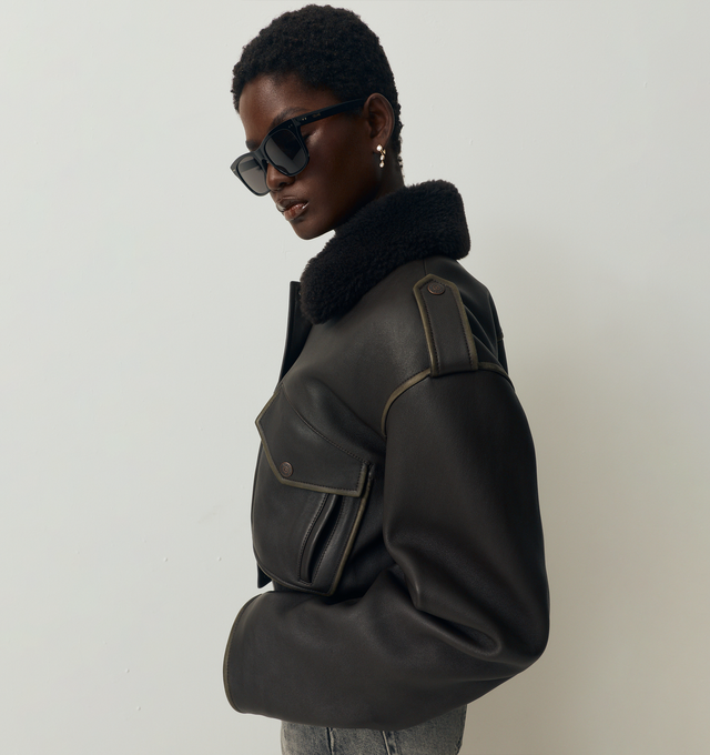 Image 3 of 5 - BROWN - ACNE STUDIOS Leather Bomber Jacket featuring soft lamb leather with a shearling collar, dropped shoulders with epaulettes, front flap pockets, side welt pockets, an elasticated hem, front snap button, zipper closure, zip sleeves, a metal logo plaque at the back neckline, relaxed fit and below-waist length. 100% Lamb leather. 100% Lamb shearling. Lining: 100% viscose.