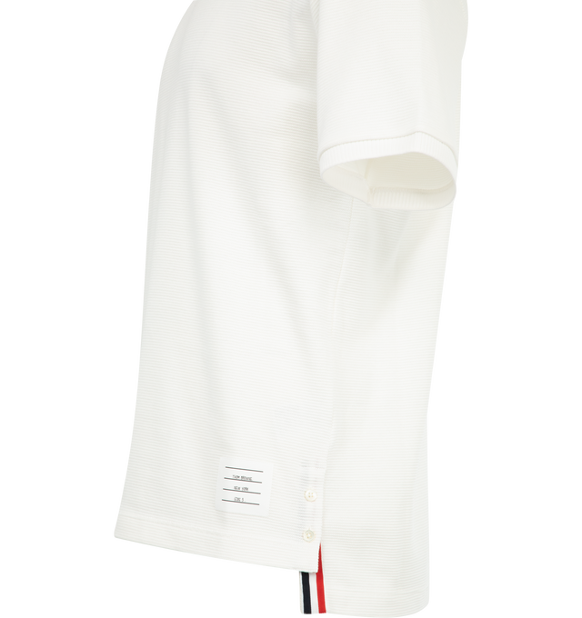 Image 3 of 3 - WHITE - THOM BROWNE Waffle Rib Cuff Tee featuring Thom Browne emblems at the hem, side vents, and collar, crew neck, short sleeves, name tag applique, buttoned side vents with signature striped grosgrain trim, dropped back hem and signature striped grosgrain loop tab. 100% cotton. Made in Italy.