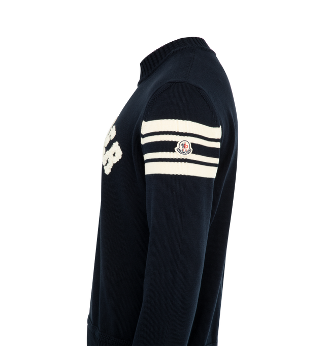 Image 3 of 3 - NAVY - MONCLER Curved Logo Knit Crewneck Sweater featuring embroidered curved logo on the front, logo emblem with stripes on the left sleeve, crew neckline, long sleeves, ribbed cuffs and hem and pullover style. Polyester/leather. Lining: polyester. Made in Bulgaria.