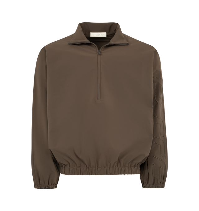 Image 1 of 3 - BROWN - FEAR OF GOD ESSENTIALS Active Trace Half Zip Track Jacket featuring perforated lining for breathability, detailed with an embroidered Essentials active trace logo on the sleeves, relaxed, rounded silhouette, high neck, half-zip front, elasticized cuffs and waist hem and Essentials signature label is at the back collar. 100% polyester.