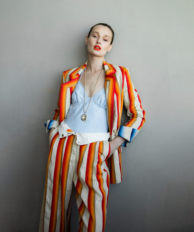Woman wearing Rosie Assoulin blue striped beach bustier with red circus striped trouser and blazer 