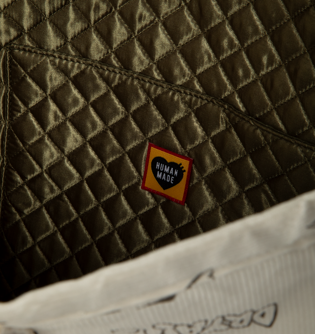 Image 3 of 3 - CREAM - Human Made Men's Corduroy Tote is crafted from finely textured cotton corduroy and features hand-drawn-style graphic artwork, interior and exterior pockets, and A3-size storage capacity. Designed for everyday functionality, this tote is lined with cushioned khaki quilting and finished with signature heart logo embroidery for a distinctive Human Made touch. Main Material: Shell: 100% Cotton. Lining: 100% Polyester. Filling: 100% Polyester. Dimensions: 16.5 x 15 x 5.5 in. Interior: Inte
