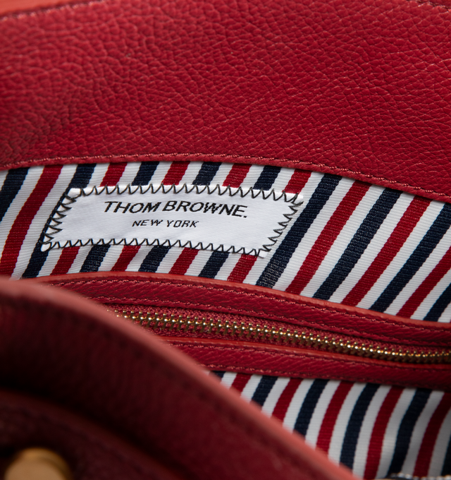 Image 4 of 4 - RED - THOM BROWNE Bolton Bag featuring padlock flap closure, top handles, key bell with RWB grosgrain trim, detachable adjustable leather shoulder strap, detachable RWB ribbon-woven chain strap, RWB stripe on front and back, adjustable side gussets with belt and stud details, interior zip pocket, slip pocket, and two smaller slip pockets, tricolor lining and signature striped grosgrain loop tab. L 33 x W 15 x H 35 cm. 100% calf full grain leather. Lining: 100% polyester. Made in Italy.