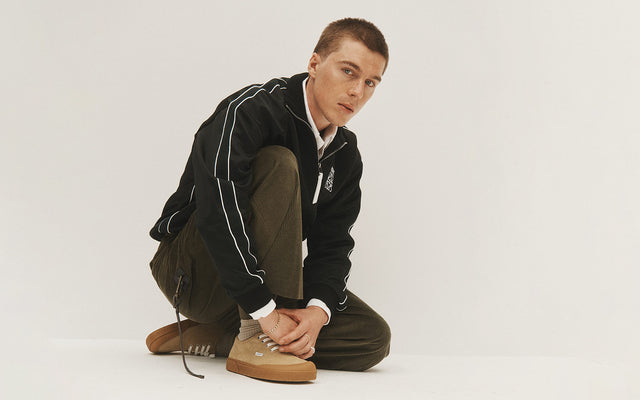 Man wearing Loewe track jacket, olive green pants, and suede Terra Vulca sneakers