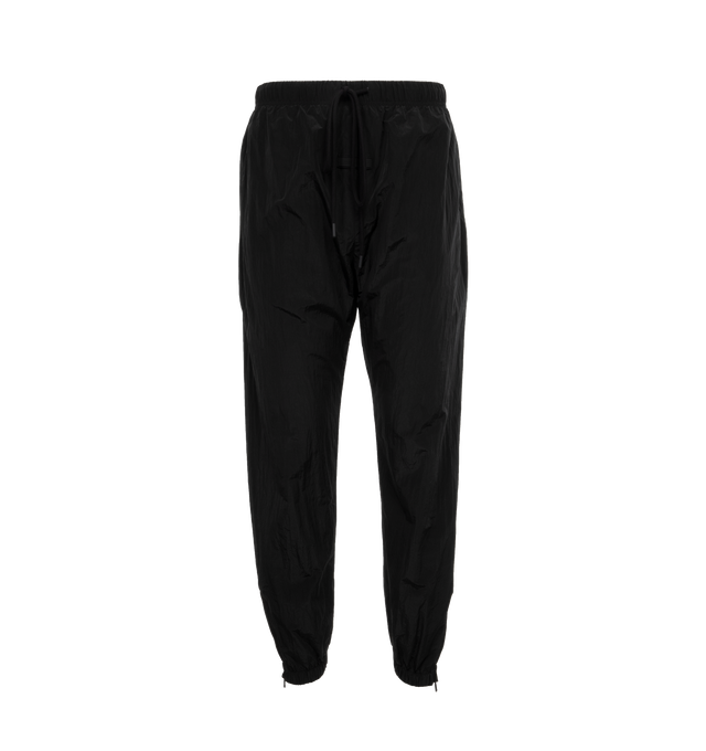 Image 1 of 4 - BLACK - FEAR OF GOD ESSENTIALS Crinkle Nylon Trackpants featuring an encased elastic waistband with elongated drawstrings, side seam pockets, an elastic hem with zipper adjustability at the ankle and a rubberized label at the center front. 100% nylon.  