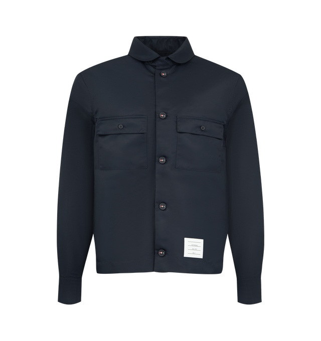 Image 1 of 3 - BLUE - Thom Browne Mens Tech Twill Shirt is crafted from lightweight technical twill. Features a button-front closure with signature RWB detailing, club collar with buttoned tab closure, buttoned flap chest pockets, buttoned cuffs, reinforced pleated back yoke with locker loop, buttoned side vents with internal RWB grosgrain trim, stepped hem, name tag appliqu, and signature striped grosgrain loop tab. Main Material: 100% Polyamide. Made in Italy.