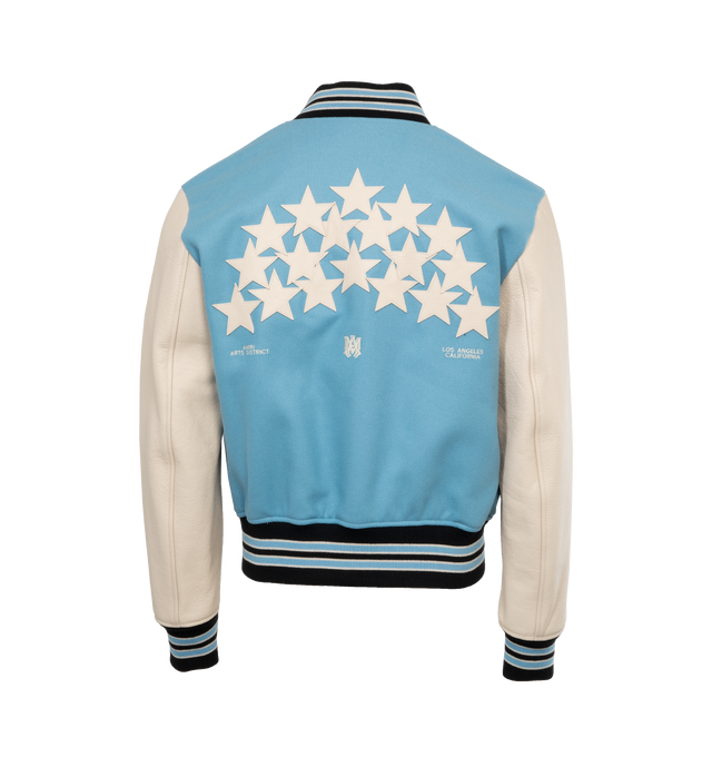 Image 2 of 4 - BLUE - AMIRI OVERSIZED STARS VARSITY JACKET crafted from durable light blue wool with leather contrast sleeves, adorned with a contellation of leather star appliques. Features contrast banded rib detailing at the waist, writsts and neck, welt zipper pockets, and classic snap button closure.  Wool shell, leather sleeves, viscose lining. Made in Italy.  