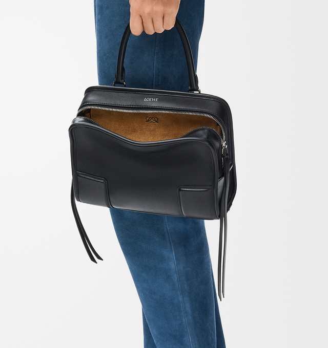 Image 2 of 16 - BLACK - Loewe Small Amazona 180 Bag in leather features a relaxed silhouette anchored by a single toron top handle, designed to be carried open, while a concealed closure secures the main compartment, three carry options: short handle, removable shoulder strap and crossbody, zip closure with two leather zip pullers, two compartments, main compartment closed with magnetic closure, internal flat pocket, left side d-ring for customization, nappa lambskin lining, and embossed double L branding.