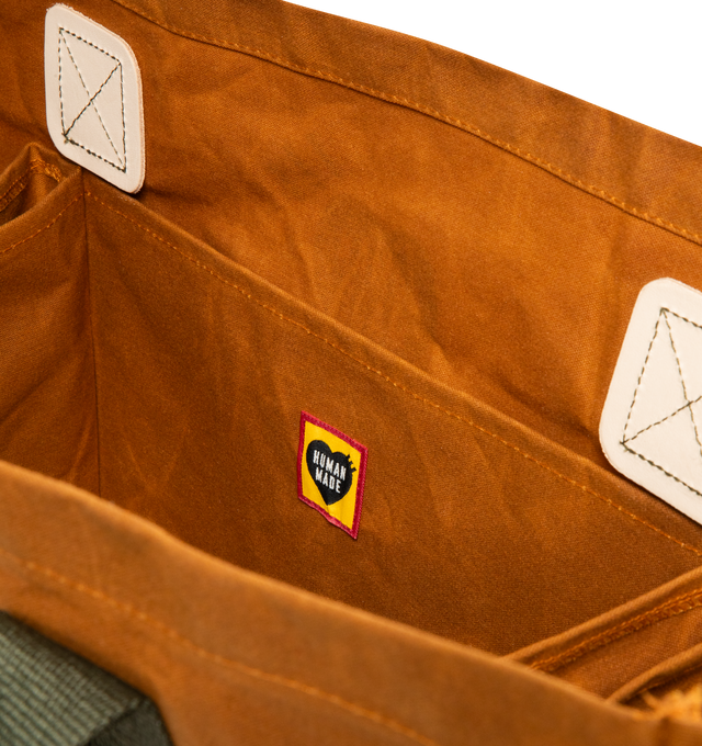 Image 3 of 3 - BROWN - HUMAN MADE Decoy Tote featuring vintage-inspired design, cotton canvas fabric, highly water-repellent with unique texture from paraffin treatment, contrasting handles, iconic camo and heart logo graphics on front and back, dye-print graphic, leather patching details and inner storage sections. 100% cotton.