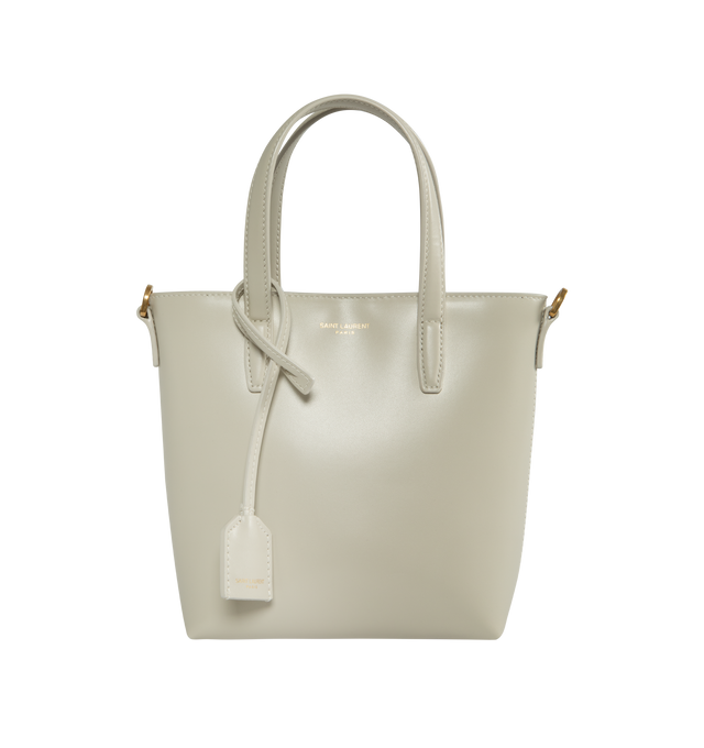 Image 1 of 3 - WHITE - Saint Laurent Mini tote bag embossed with "Saint Laurent Paris" and decorated with a removeable leather-encased Cassandre charm. Features magnetic snap closure, flat leather top handles and an adjustable and detachable strap for multiple carry options.  Lambskin leather with bronze-tone hardware. Measures 7.1" X 6.7" X 3.1" with handle drop 3.3" and strap drop 19.7". Made in Italy.  