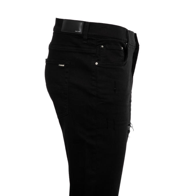 Image 2 of 2 - BLACK - AMIRI MX1 classic stretch button fly denim jeans with fading, distressing, and whiskering throughout. Mid-rise, belt loops at waistband and five-pocket styling. Quilted leather trim in black at front legs. Logo plaque at back pocket. 92% Cotton, 6% Elastomultiester, 2% Elastane. Made in United States.