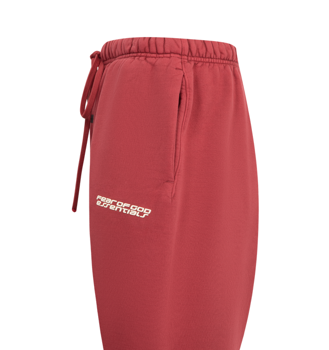 Image 3 of 3 - RED - FEAR OF GOD ESSENTIALS Heavy Fleece Classic Sweatpant featuring 520gsm heavy cotton fleece, pigment-dyed, relaxed silhouette tapers into an elastic hem, HD-printed Fear of God Essentials lockup, encased elastic waistband with elongated drawcords, side seam pockets and a Fear of God Essentials rubberized label stitched at the center front. 100% cotton.