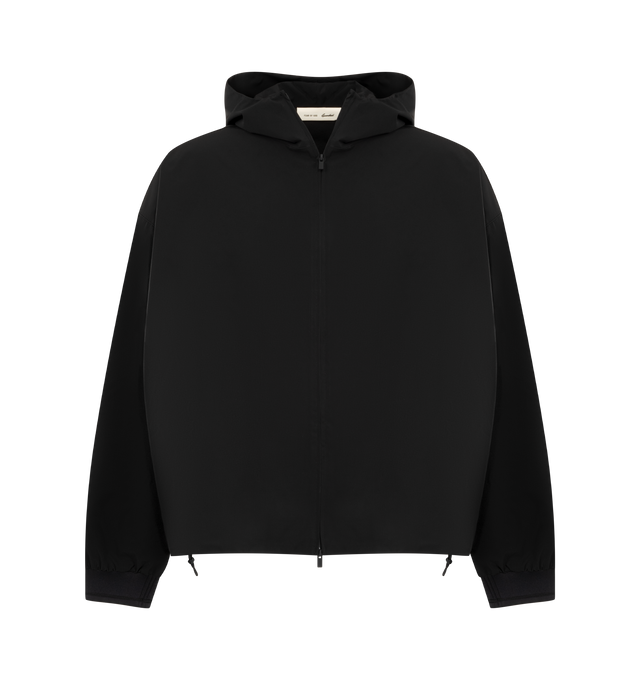 Image 1 of 3 - BLACK - Fear of God Essentials Mens Full Zip Hooded Anorak is crafted from polyester. Features a relaxed cropped fit, mock-neck hood, full front zip closure, side pockets, ribbed cuffs, adjustable bungee waist with toggle, stretch perforated lining, puff-printed FOG graphic on the sleeves, and an Essentials logo label. Main Material: 100% Polyester; Lining: 100% Stretch Perforated Polyester.