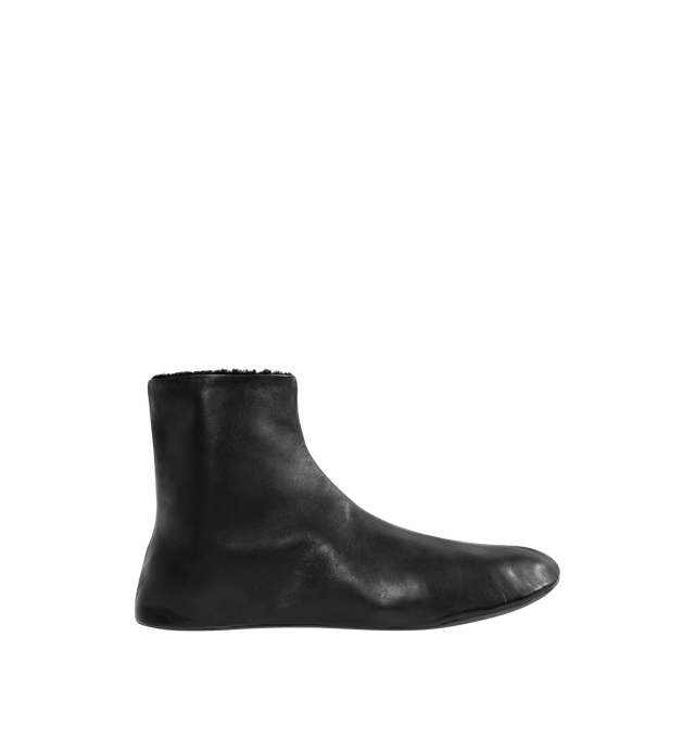 Image 1 of 4 - BLACK - THE ROW Stella Boot featuring minimal ankle boot in smooth nappa leather with inner side zip closure, soft shearling lining and flexible rubber-coated sole. 100% lambskin leather. Synthetic sole. Made in Italy.