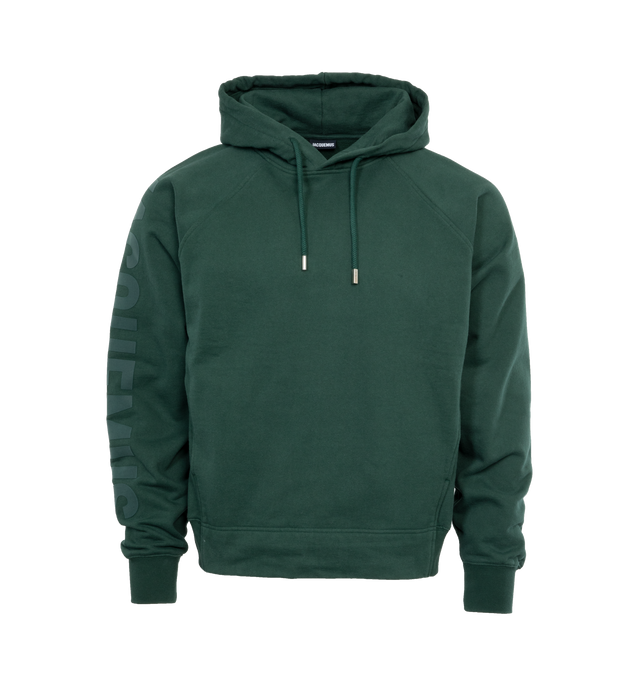 Image 1 of 4 - GREEN - JACQUEMUS LE HOODIE TYPO is a long sleeve logo hoodie with a classic fit, adjustable drawstring hood, raglan sleeves, engraved circle, square tips, tone-on-tone logo on right sleeve, side seam pockets, ribbed cuffs and back hem. 100% cotton 