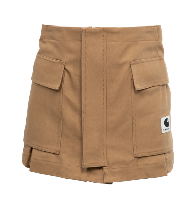 Image 1 of 4 - BROWN - SACAI X CARHARTT WIP Canvas shorts with zip and double button closure, pockets and front logo patch, hammer loop detail at the back pocket,  belt loops, gold tone hardware. Features skirt overlay in front with cargo pockets, zip and button closure. Women's Japanese sizing. JP size 1 = US X-small. JP size 2 = US small. JP size 3 = US medium. JP size 4 = US large.   