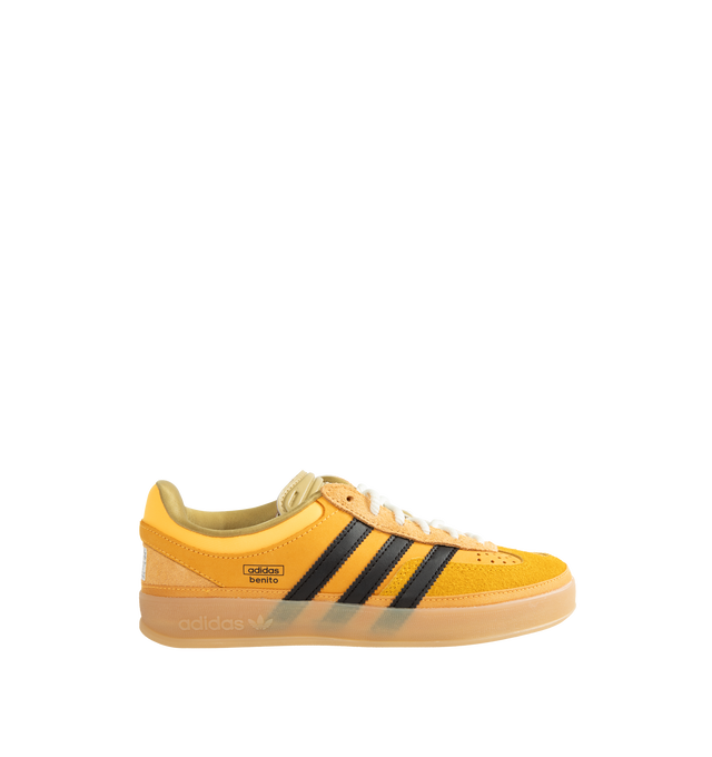 Image 1 of 5 - YELLOW - Adidas Originals x Bad Bunny Men's Gazelle Indoor Shoes feature the latest release from the ongoing adidas Originals by Bad Bunny collaboration, reimagining the iconic Gazelle Indoor silhouette through the artist's distinctive creative lens. Crafted with a premium leather upper, this statement sneaker combines heritage terrace style with contemporary design details, while a textile lining enhances comfort and a durable gum outsole provides everyday traction. Main Material: Leather Up
