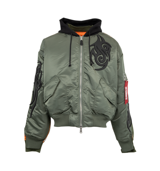 Image 1 of 3 - GREEN - VETEMENTS Tribal Reworked Bomber jacket featuring front zip closure, drawstring hood, ribbed cuffs and hem, front pockets with flap and patch designs throughout.