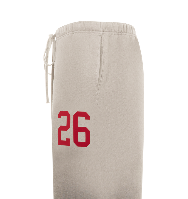 Image 3 of 3 - NEUTRAL - FEAR OF GOD ESSENTIALS Lounge Sweatpant featuring core fleece treated with a vintage wash, wide-leg silhouette, a 26 HD print graphic on the leg, encased elastic waistband with elongated drawcords, side seam pockets and a Fear of God Essentials rubberized label stitched at the center front. 100% cotton.