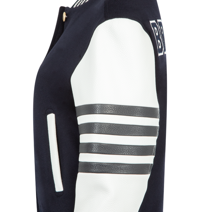 Image 3 of 3 - NAVY - THOM BROWNE Browne 65 Varsity Jacket featuring cashmere with leather sleeves, bold BROWNE. lettering and the number 65 on back appliqud in layered silk and cashmere with satin-stitched edges, 4-bar at the sleeve, front button closure, ribbed bomber collar, cuffs, and hem with 4-bar tipping, welt hand pockets with leather trim, three interior pockets, quilted interior, layered appliqu, relaxed fit and signature striped grosgrain loop tab. 100% wool. Lining: 100% silk. Made in Italy.