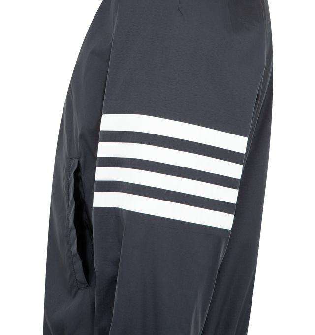 Image 3 of 3 - NAVY - THOM BROWNE Shiny Ripstop Raglan Track Jacket featuring front hidden zip closure, stand collar, welt hand pockets, interior snap pocket, raglan sleeves, elasticated cuffs and hem, 4-bar detailing, name tag appliqu and signature striped grosgrain loop tab. 81% polyamide, 19% polyester. Made in Italy.