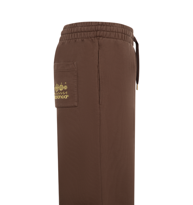 Image 3 of 3 - BROWN - Casablanca Men's Embroidered Pintuck Joggers are crafted from premium cotton and feature a relaxed silhouette with pintuck detailing, an elasticated drawstring waistband, ribbed cuffs, side pockets, and signature embroidered branding. These designer joggers combine exceptional everyday comfort with Casablanca's refined luxury sportswear aesthetic, creating an elevated essential for casual styling. Main Material: 100% Cotton.