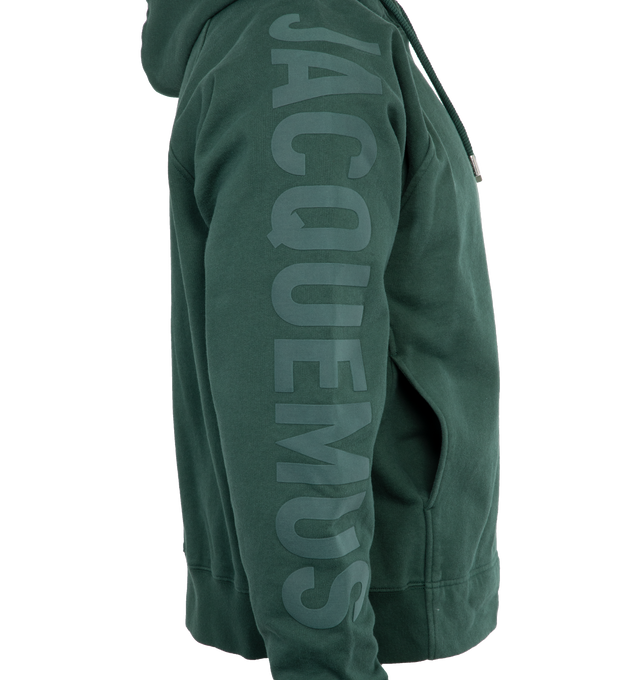 Image 3 of 4 - GREEN - JACQUEMUS LE HOODIE TYPO is a long sleeve logo hoodie with a classic fit, adjustable drawstring hood, raglan sleeves, engraved circle, square tips, tone-on-tone logo on right sleeve, side seam pockets, ribbed cuffs and back hem. 100% cotton 