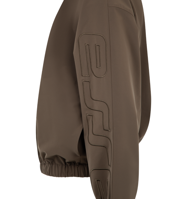 Image 3 of 3 - BROWN - FEAR OF GOD ESSENTIALS Active Trace Half Zip Track Jacket featuring perforated lining for breathability, detailed with an embroidered Essentials active trace logo on the sleeves, relaxed, rounded silhouette, high neck, half-zip front, elasticized cuffs and waist hem and Essentials signature label is at the back collar. 100% polyester.