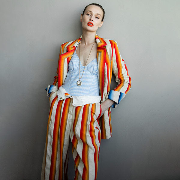 Woman wearing Rosie Assoulin blue striped beach bustier with red circus striped trouser and blazer