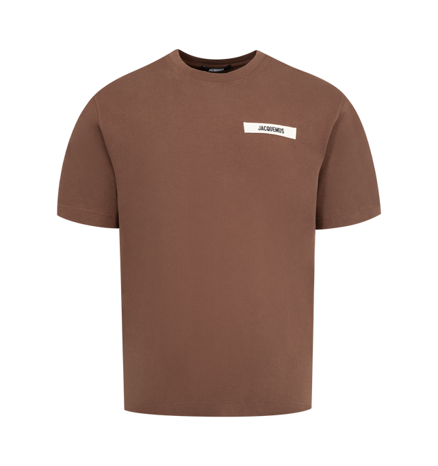 Image 1 of 2 - BROWN - JACQUEMUS Grosgrain Logo T-Shirt featuring relaxed fit, organic cotton jersey, ribbed crew neck, embroidered grosgrain logo on the chest and short sleeves. 100% cotton. Made in Portugal.