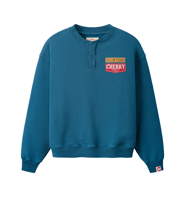 Image 1 of 7 - BLUE - Cherry LA Men's Patch Work Henley Crew is crafted from custom cotton fleece and features a boxy-fit silhouette with patchwork detailing at the chest and a concealed-button Henley placket. Designed for everyday comfort, this elevated sweatshirt is finished with hidden front buttons and a signature branded label at the cuff. Main Material: Custom Cotton Fleece. Made in Los Angeles, California.