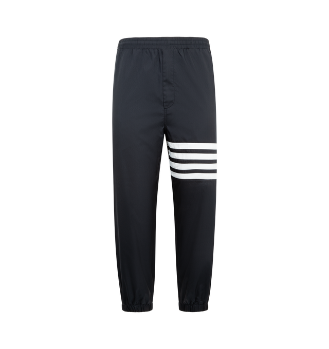 Image 1 of 3 - NAVY - THOM BROWNE Shiny Ripstop 4 Bar Track Pant featuring elasticated waistband with internal drawstring, zip fly, hand pockets and back pocket with hidden zips, elasticated cuffs, mesh lining, 4-bar detailing and signature striped grosgrain loop tab. 81% polyamide, 19% polyester. Made in Italy.