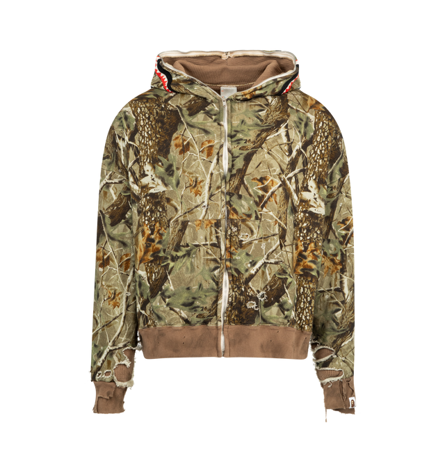 Image 1 of 2 - BROWN - SAINT MICHAEL Shark Bape Zip Hoodie featuring a textured thermal fabric lining, real tree camouflage pattern, boxy silhouette, double-zip closure that zips all the way up to the top of the hood, detailed with a shark mouth and eyes on the front and brand lettering in red with yellow outline on the back, signature distressed finishing and waffle knit lining. 100% cotton. Made in Japan.