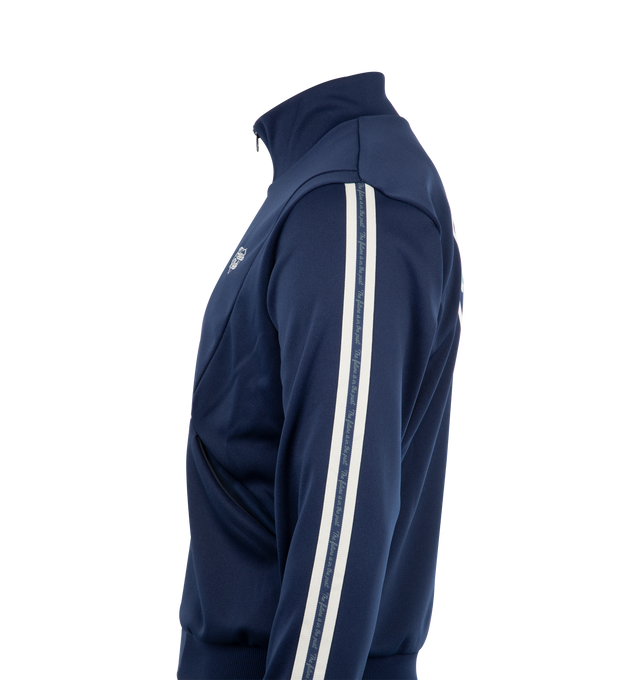 Image 3 of 3 - NAVY - HUMAN MADE Track Jacket featuring zip front closure, stand collar, a heart logo in thick flocky print, an embroidered logo on the front and jacquard tape on both sleeves. 100% polyester.