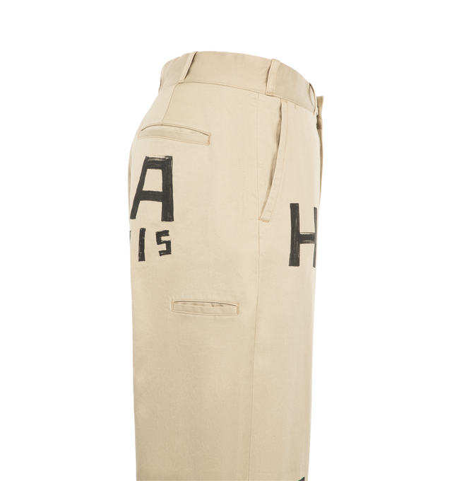 Image 3 of 3 - NEUTRAL - Human Made Men's Wide Fit Chino Pants are crafted from high-density cotton chino cloth and feature a wide-leg silhouette with a high-rise waist and relaxed fit. Designed with a crisp handfeel and subtle sheen, these statement trousers are detailed with hand-painted-style graphic artwork, a printed brand message inside the back waistband, and a signature heart-shaped button at the back left pocket. Main Material: 100% Cotton.
