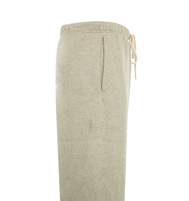 Image 3 of 3 - NEUTRAL - Fear of God Essentials Mens Classic Sweatpants are crafted from heavyweight 380 GSM cotton-blend core fleece. Feature a classic relaxed fit with tapered legs, elasticized waistband with bungee drawcord, side-seam pockets, elastic ankle cuffs, puff-printed Fear of God and Essentials branding, and an Essentials logo label. Main Material: 80% Cotton, 20% Polyester.
