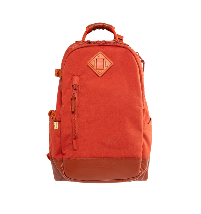 Image 1 of 3 - ORANGE - VISVIM Cordura 20L Backpack featuring custom zip fastener, french vegetable tanned lamb leather details, neoprene-lined laptop sleeve, designated audio player pocket, headphone port, rear padded panel, padded shoulder straps and signature leather brand tab. 100% nylon.