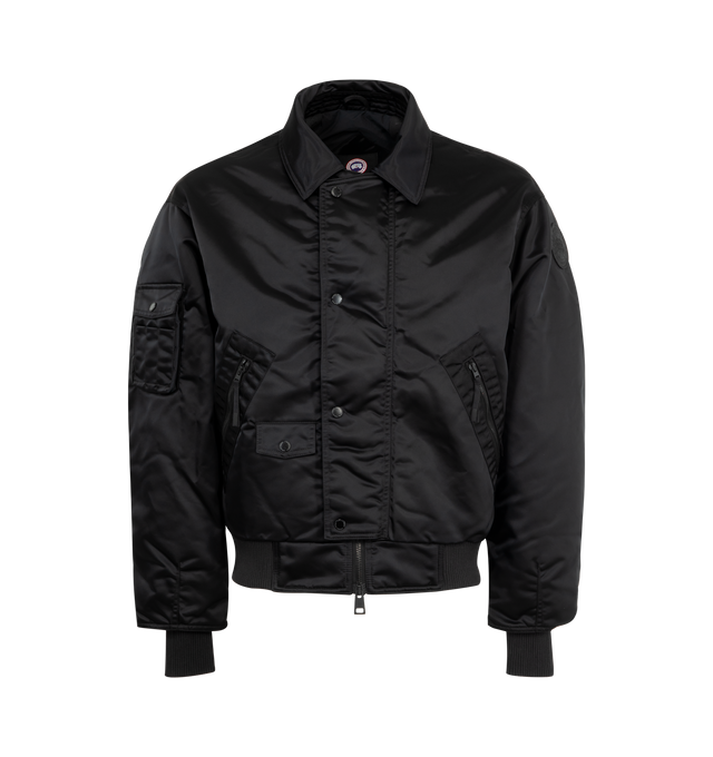 Image 1 of 3 - BLACK - CANADA GOOSE Seguin Aviator Bomber featuring double placket with coin-snap closure, dropped shoulders, rib-knit cuffs and hem, interior backpack straps for hands-free carrying capabilities, two fleece-lined zippered hand pockets, one sleeve pocket, one pen pocket with snap closure and ribbed waist. 100 % recycled polyamide. Made in Canada.