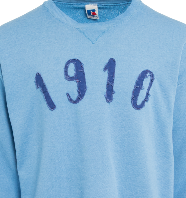 Image 3 of 4 - BLUE - This powder blue upcycled vintage sweatshirt features "1910" applique at the front and Transnomadica label at the back. 50% cotton / 50% polyester with the size XL on its original vintage label. Measurements: 23 inches in length from neckline to front hem, 25 inches from shoulder-to-shoulder, 25 inches from armpit-to-armpit, 22 inches from top sleeve seam to top of wrist.This collection of vintage sweatshirts, exclusively for 1910 at Hirshleifers, each featuring a hand-crafted 1910 a 