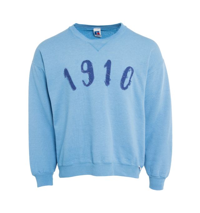 Image 1 of 4 - BLUE - This powder blue upcycled vintage sweatshirt features "1910" applique at the front and Transnomadica label at the back. 50% cotton / 50% polyester with the size XL on its original vintage label. Measurements: 23 inches in length from neckline to front hem, 25 inches from shoulder-to-shoulder, 25 inches from armpit-to-armpit, 22 inches from top sleeve seam to top of wrist.This collection of vintage sweatshirts, exclusively for 1910 at Hirshleifers, each featuring a hand-crafted 1910 a 