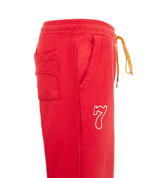 Image 4 of 4 - RED - Rhude Desert Racing Script Cuffed Sweatpant is crafted from cotton and features a relaxed silhouette with elasticated cuffs for a tapered fit. Designed with Desert Racing Script graphics, an elasticated waistband, and functional pocket detailing for everyday comfort. Main Material: 100% Cotton. Made in USA.