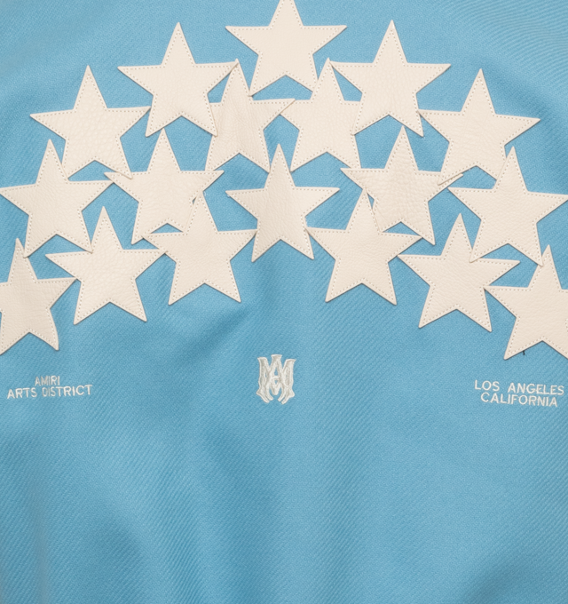 Image 4 of 4 - BLUE - AMIRI OVERSIZED STARS VARSITY JACKET crafted from durable light blue wool with leather contrast sleeves, adorned with a contellation of leather star appliques. Features contrast banded rib detailing at the waist, writsts and neck, welt zipper pockets, and classic snap button closure.  Wool shell, leather sleeves, viscose lining. Made in Italy.  