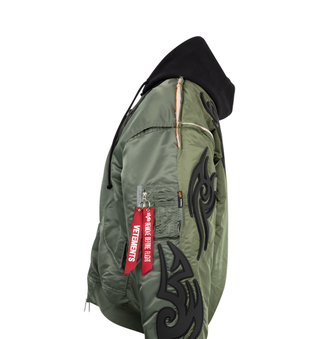 Image 3 of 3 - GREEN - VETEMENTS Tribal Reworked Bomber jacket featuring front zip closure, drawstring hood, ribbed cuffs and hem, front pockets with flap and patch designs throughout.